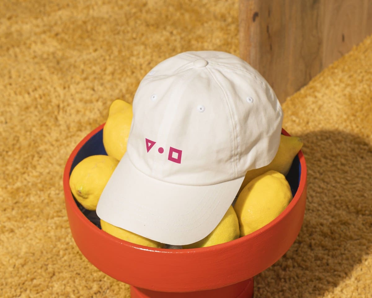 Creme pet met de drie logovormen van Studio Vorm en Gever in magenta
