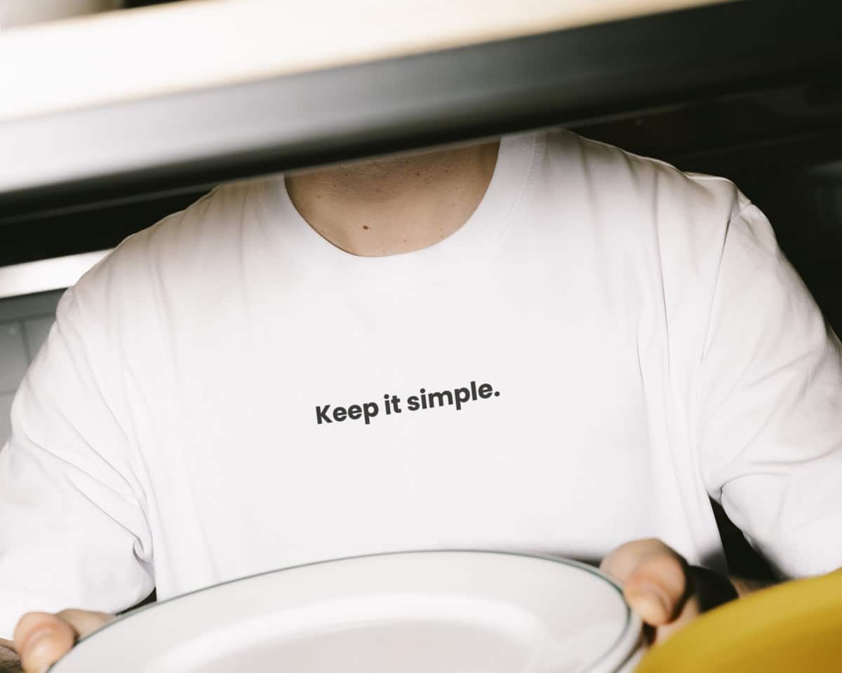 Wit T-shirt met de opdruk Keep it simple, gedragen in een keuken