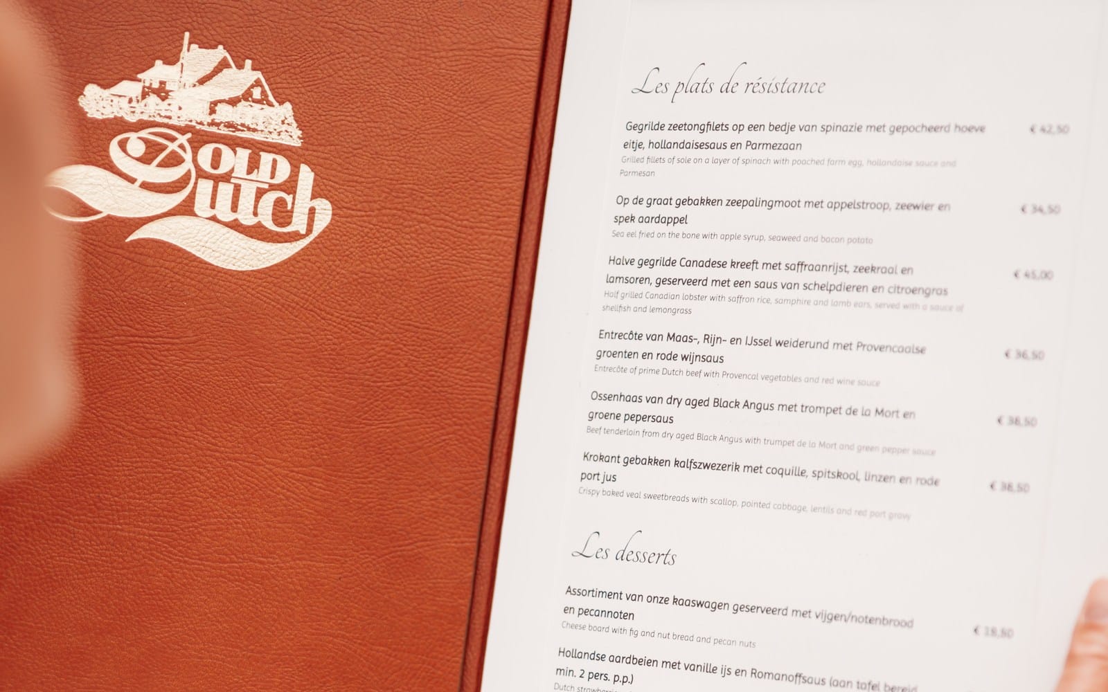 Leren menumap van Old Dutch met het logo in preegdruk, opengeslagen bij de hoofdgerechten