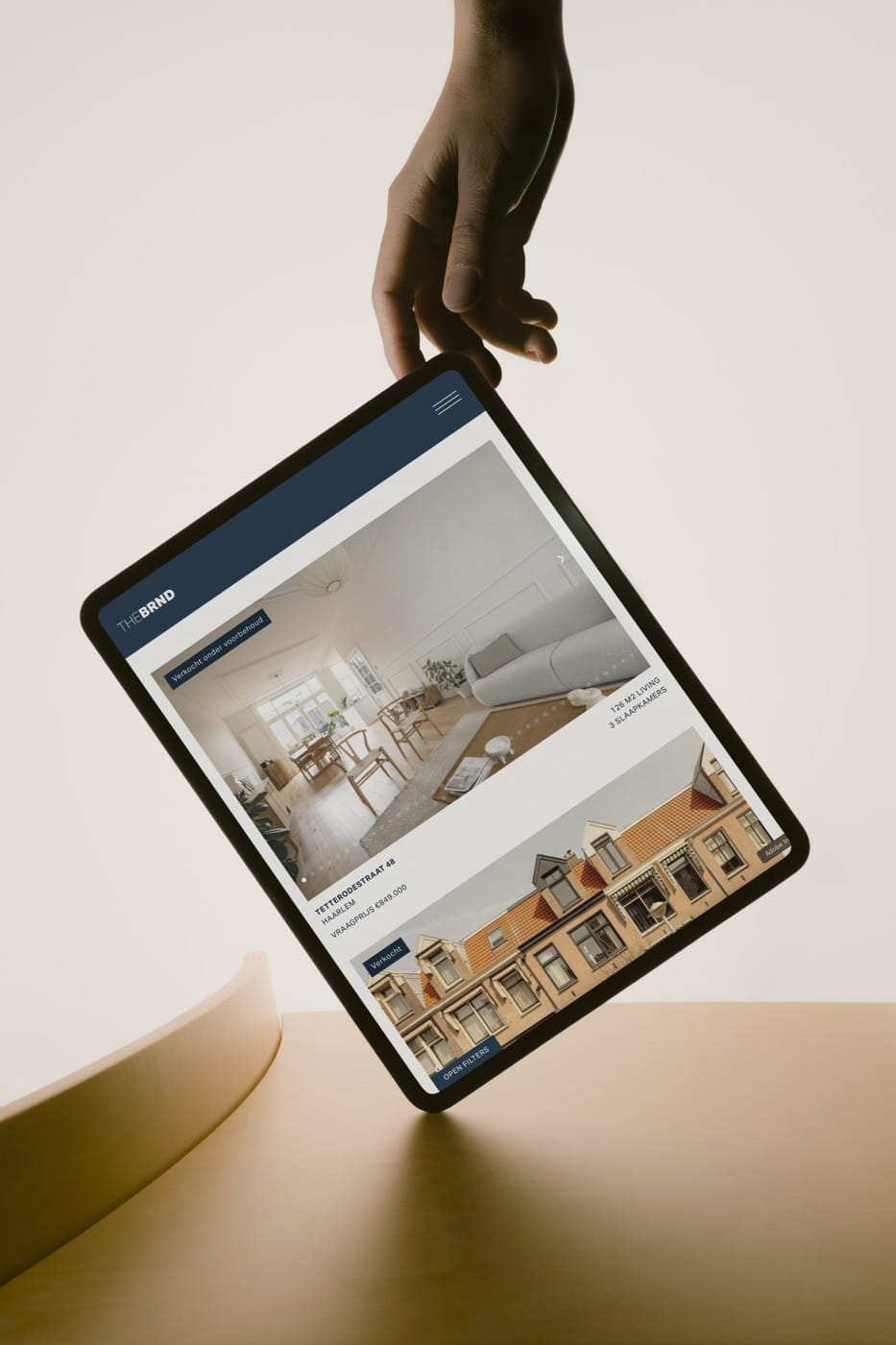Website van The BRND Brokerage op een tablet die uit een hand hangt