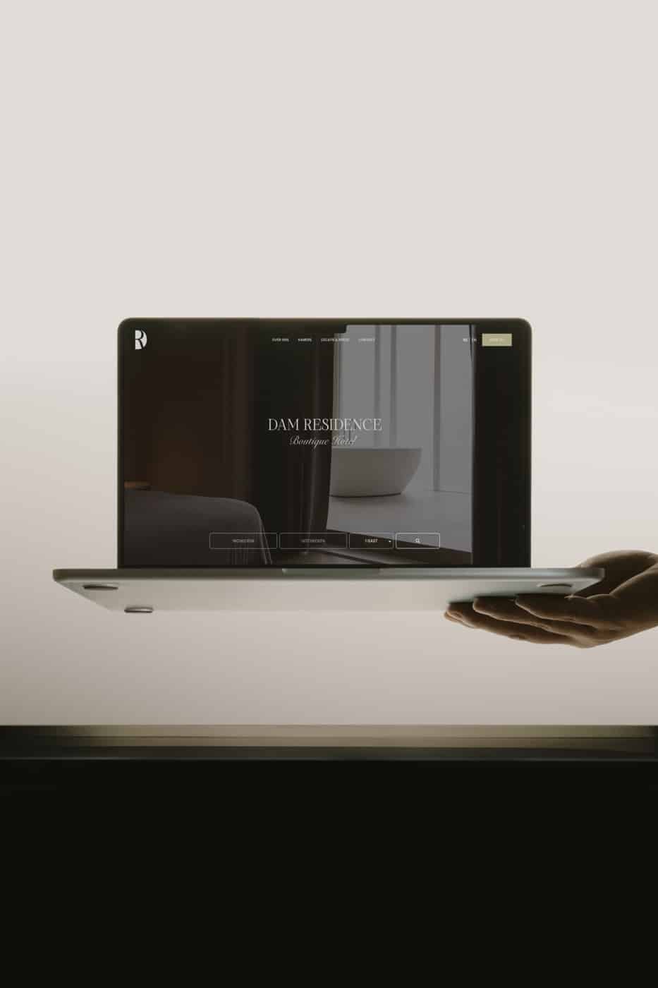 Website van DAM Residence op een laptop die in een hand rust