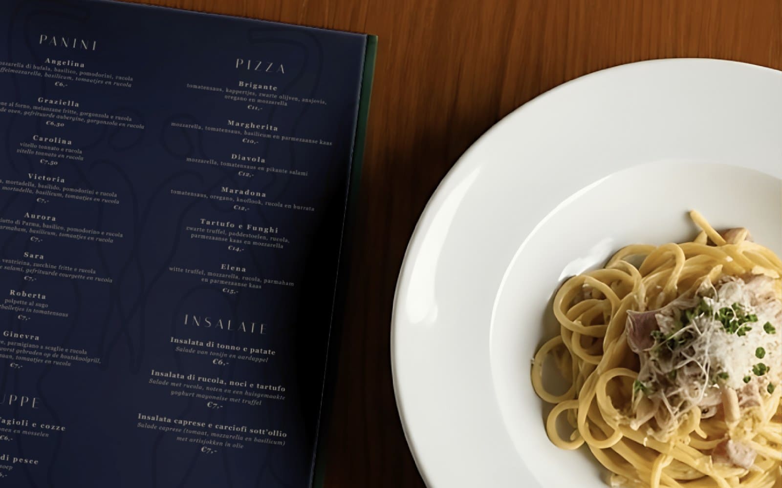 Diepblauwe menukaart van La Tarantella naast een bord pasta
